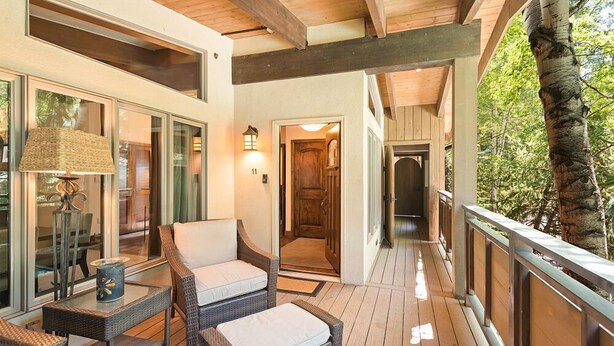 A covered outdoor area with wicker furniture and a lamp, leading to a wooden door. - Little Nell Condominiums Unit 11 | Top Floor Condo with Mountain Views, 3 Blocks to Gondola (Aspen)