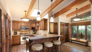 A kitchen with wooden cabinets, a large island with stools, and pendant lighting. - Little Nell Condominiums Unit 11 | Top Floor Condo with Mountain Views, 3 Blocks to Gondola (Aspen)