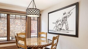 A dining area with a round table, wooden chairs, and a pendant light. - Fasching Haus Unit 12 | Lower Level Deluxe Condo w/ Open Living Area & Gas Fireplace (Aspen)