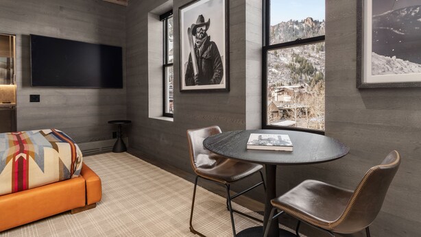 Une pièce moderne avec une grande fenêtre, un canapé, une table avec des chaises et des tableaux encadrés accrochés aux murs.