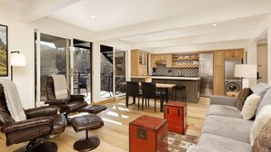 Ein modernes Wohnzimmer mit Ledersofas, einem Essbereich und einer Küche mit gemustertem Fliesenspiegel.