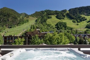 Relax in a hot tub on a balcony with breathtaking views of the surrounding mountains and lush greenery.
