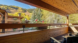 A wooden deck with benches and a view of a forested hillside.