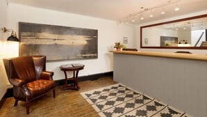 A reception area with a large abstract painting, a leather chair, a small table, a patterned rug, and a mirror above the reception desk. - Independence Square 211 | Chic Hotel Room with Mountain Views, A/C, & Rooftop Hot Tub (Aspen)