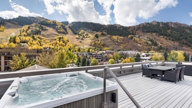 A rooftop patio with a hot tub, outdoor furniture, and a view of a mountainous landscape. - Independence Square 211 | Chic Hotel Room with Mountain Views, A/C, & Rooftop Hot Tub (Aspen)