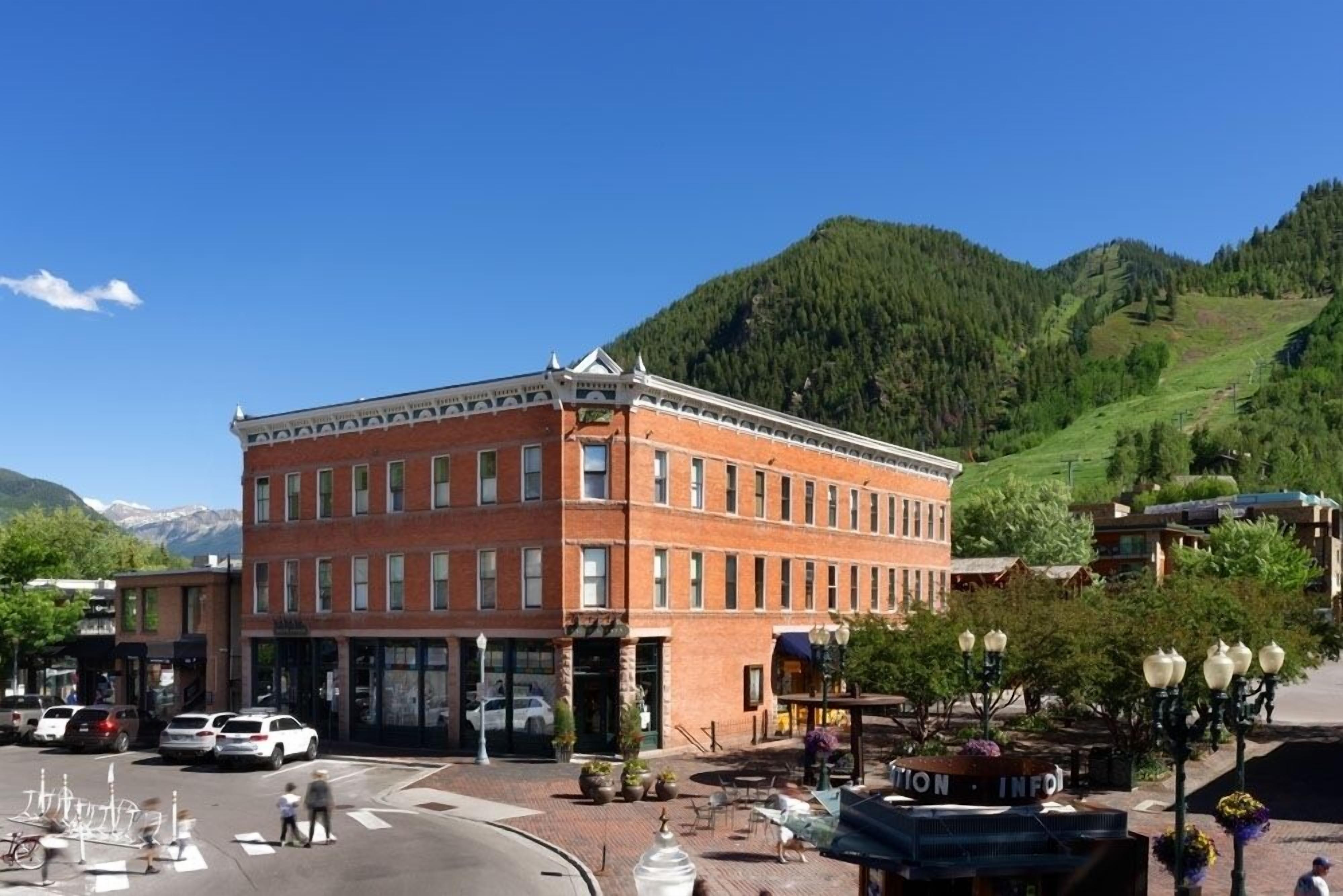 A multi-story brick building with a flat roof, large windows, and a central entrance.