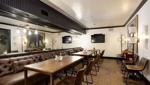 A restaurant with a long counter, leather booth seating, and a television mounted on the wall. - Independence Square 211 | Chic Hotel Room with Mountain Views, A/C, & Rooftop Hot Tub (Aspen)
