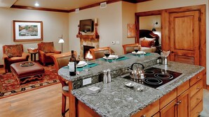 Ein geräumiges Wohnzimmer mit Kamin, einer Essecke mit einer Granitinsel und einer gemütlichen Sitzecke mit gemusterten Kissen.