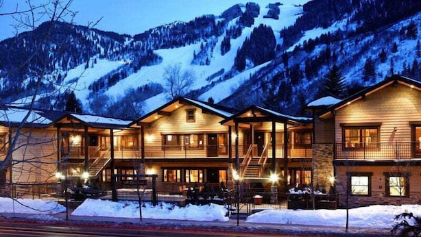 Eine Lodge mit mehreren Holzhäuschen, einem überdachten Außenbereich und Blick auf schneebedeckte Berge.