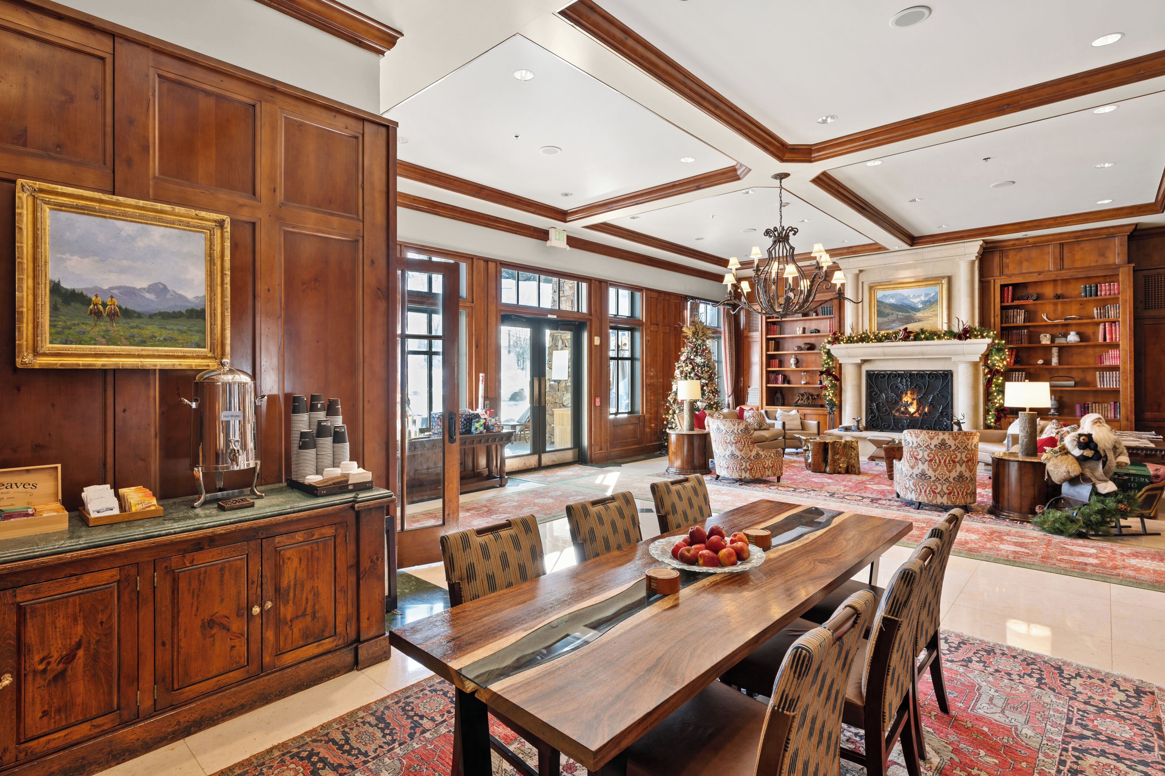 A spacious dining area with a wooden table and chairs, a fireplace, and a bookshelf.