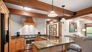 Una cocina moderna con armarios de madera, una isla grande e iluminación colgante.