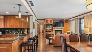 A spacious kitchen with wooden cabinets, a central island, and bar stools. There is a dining area with a wooden table and chairs. - The Ritz-Carlton Club | 3 BR Residence WR Premier 2409, Ski-in & Ski-out Resort in Aspen Highlands (Aspen)