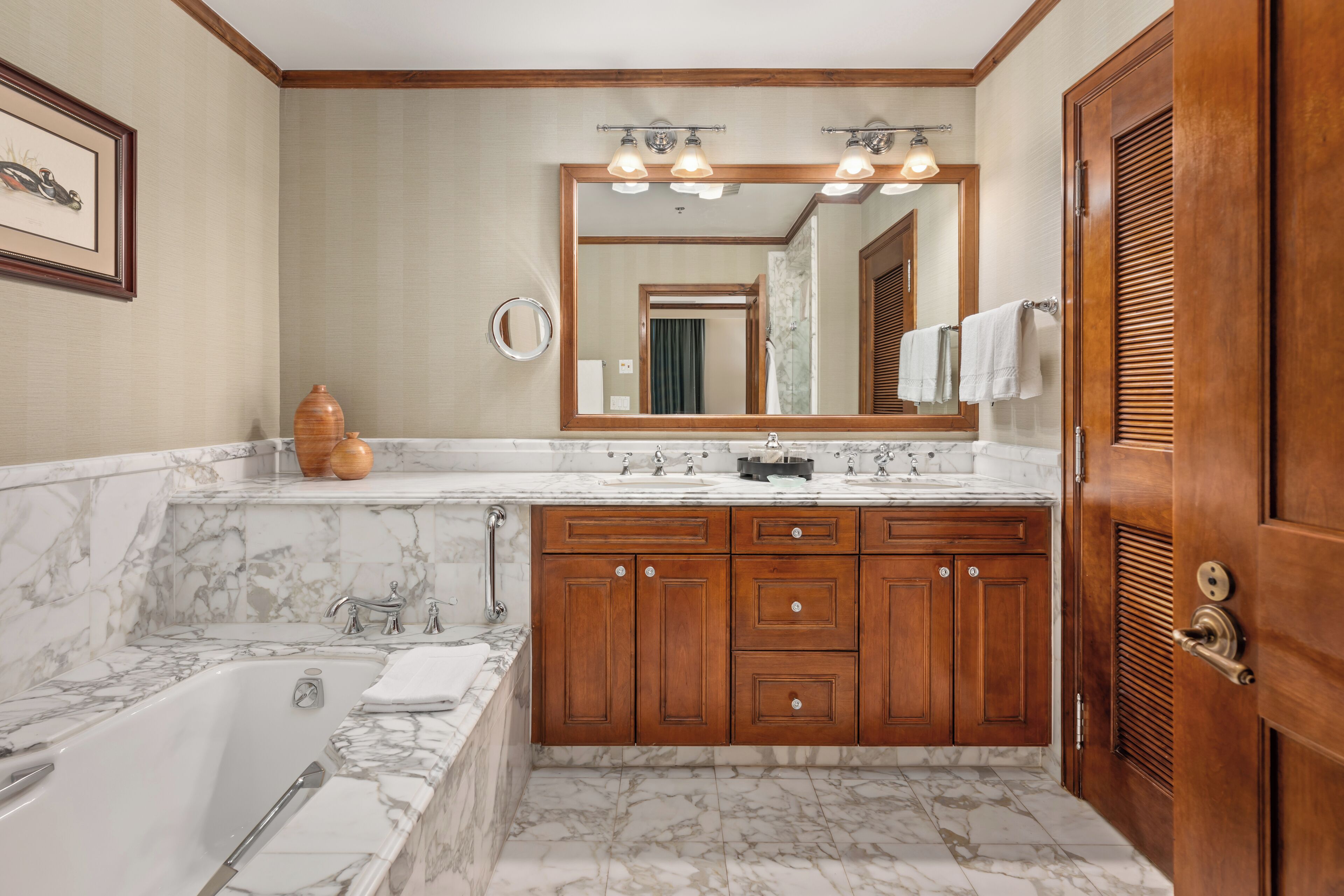 A bathroom with a marble sink, wooden vanity, and a large mirror.