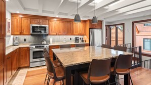 Una cucina moderna con mobili in legno, elettrodomestici in acciaio inossidabile e una grande isola con sgabelli da bar.