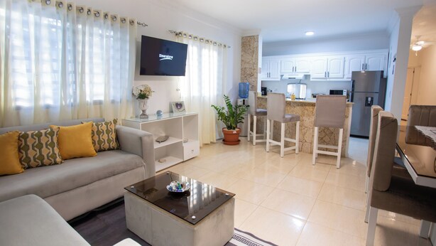 A modern living room with a sofa, coffee table, and a flat-screen TV. - MB Apartment A (Puerto Plata)