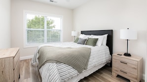 A bedroom with a bed, bedside tables, a ceiling fan, and a window with blinds. - Victory Views Estate: Luxury Guest Loft (South Bend)