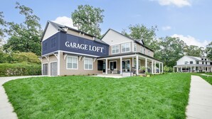 A two-story house with a 'Garage Loft' sign, a front porch, and a well-maintained lawn. - Victory Views Estate: Luxury Guest Loft (South Bend)