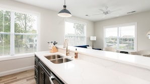 A modern kitchen with a white countertop, stainless steel sink, and a pendant light. - Victory Views Estate: Luxury Guest Loft (South Bend)