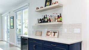 A kitchen with dark blue cabinets, a white countertop, and a variety of bottles on a shelf. - Victory Views Main House: Luxury Home for 20 Ppl (South Bend)