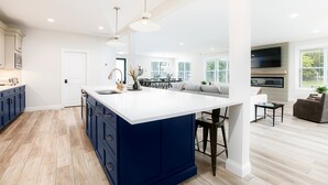 A modern kitchen with a large island, white countertops, and blue cabinetry.