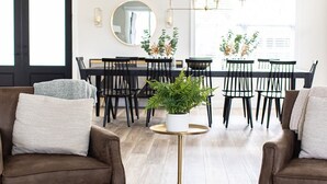 A modern living room with a sofa, a coffee table, and a dining area with a chandelier.