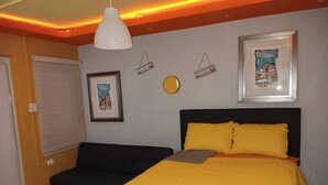 Ein Schlafzimmer mit einem Bett, einer schwarzen Bank, einer weißen Pendelleuchte und zwei Willkommensschildern.