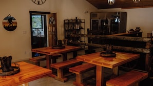 A rustic interior with wooden tables and benches, a clock on the wall, and a kitchen area in the background. - Silver Ridge Ranch (Easton)
