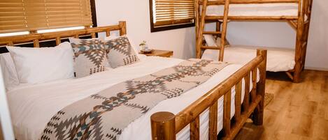 A room with a wooden bed, a bunk bed, and a window with blinds.