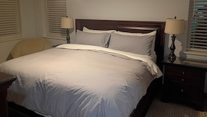 Ein Schlafzimmer mit einem Bett, zwei Nachttischlampen, einem Sessel und einer Kommode.