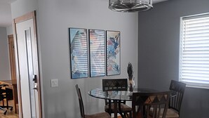 Ein Essbereich mit rundem Tisch, Stühlen, einer Pendelleuchte und abstrakter Wandkunst.