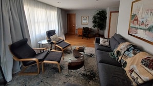 Ein Wohnzimmer mit einer Couch, zwei Sesseln, einem Couchtisch und einem Essbereich mit Tisch und Stühlen.