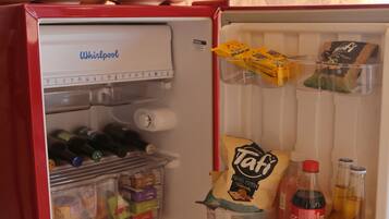 A compact refrigerator with a built-in ice maker, a freezer compartment, and a shelf for beverages.