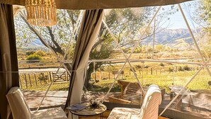 A cozy tented accommodation with a bed, chairs, and a hanging light fixture. - Ecoglamping Tafí del Valle (Tafi del Valle)