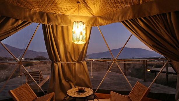 A cozy interior with a hanging light fixture, a small round table, and two wooden chairs. - Ecoglamping Tafí del Valle (Tafi del Valle)