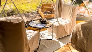 A cozy interior with a hanging light fixture, a wooden table, and a cushioned seating area. - Ecoglamping Tafí del Valle (Tafi del Valle)