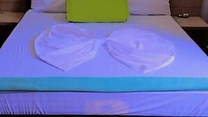 Un lit bien fait, avec du linge de lit blanc et un coussin vert, une tête de lit en bois et une table de chevet avec une lampe.