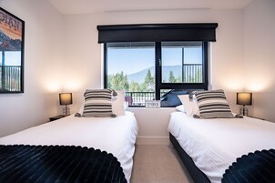 Una habitación doble con dos camas, un ventanal con vistas a las montañas y un balcón.