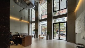 A spacious lobby with a reception desk, large windows, and a high ceiling with exposed ductwork. - Modern studio with parking - Murphy bed (Quito)