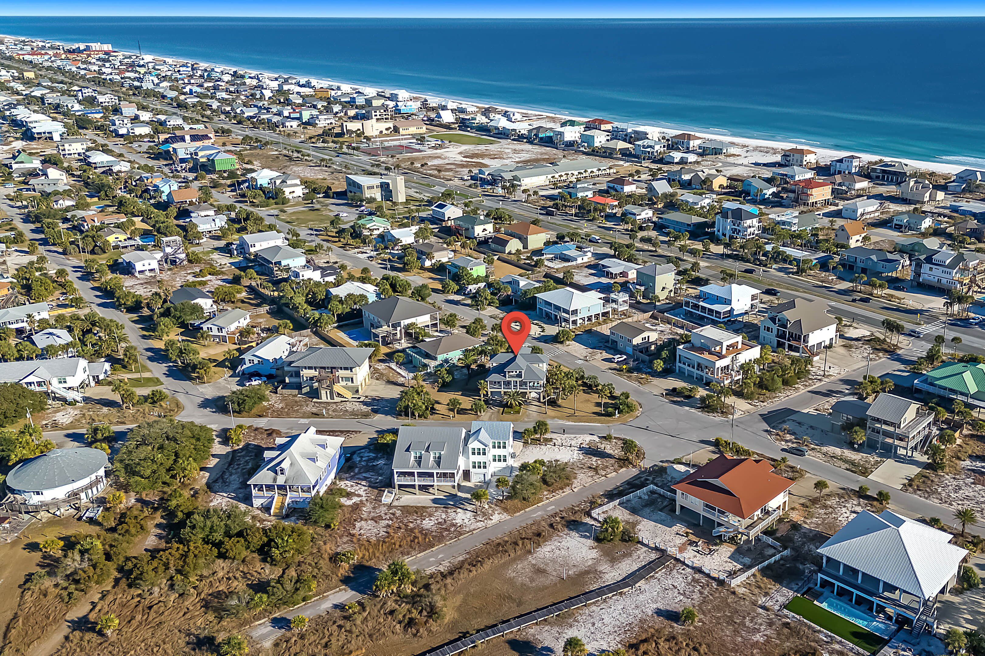 An aerial view of a coastal residential area with houses, roads, and a beach.