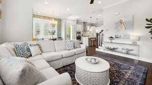 A modern living room with a white sectional sofa, a round coffee table, and a ceiling fan.