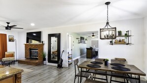 Amplia sala de estar con chimenea, mesa de comedor y ventilador de techo.