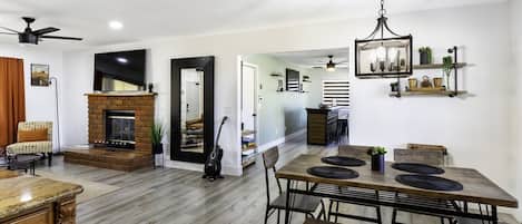 Amplia sala de estar con chimenea, mesa de comedor y ventilador de techo.