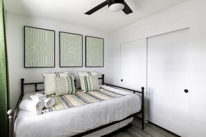 A neatly made bed with a striped blanket, a ceiling fan, and three patterned wall art pieces. - Sky Harbor House - Hot Tub + Great Backyard Space (Yucca Valley)