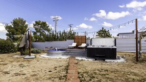 Un patio trasero con jacuzzi, mobiliario exterior y un sendero de piedra.