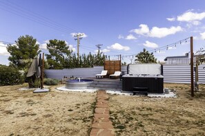 A backyard with a hot tub, outdoor seating, and a stone pathway. - Sky Harbor House - Hot Tub + Great Backyard Space (Yucca Valley)