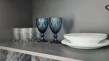 A kitchen shelf with two blue glass bowls, a white plate, and a marble backsplash.
