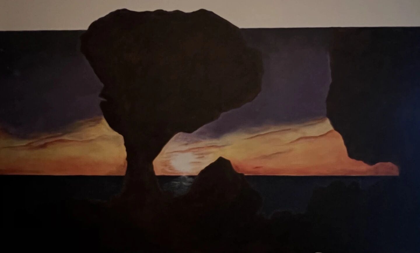 Een schilderij van een profiel van een persoon voor een ondergaande zon.