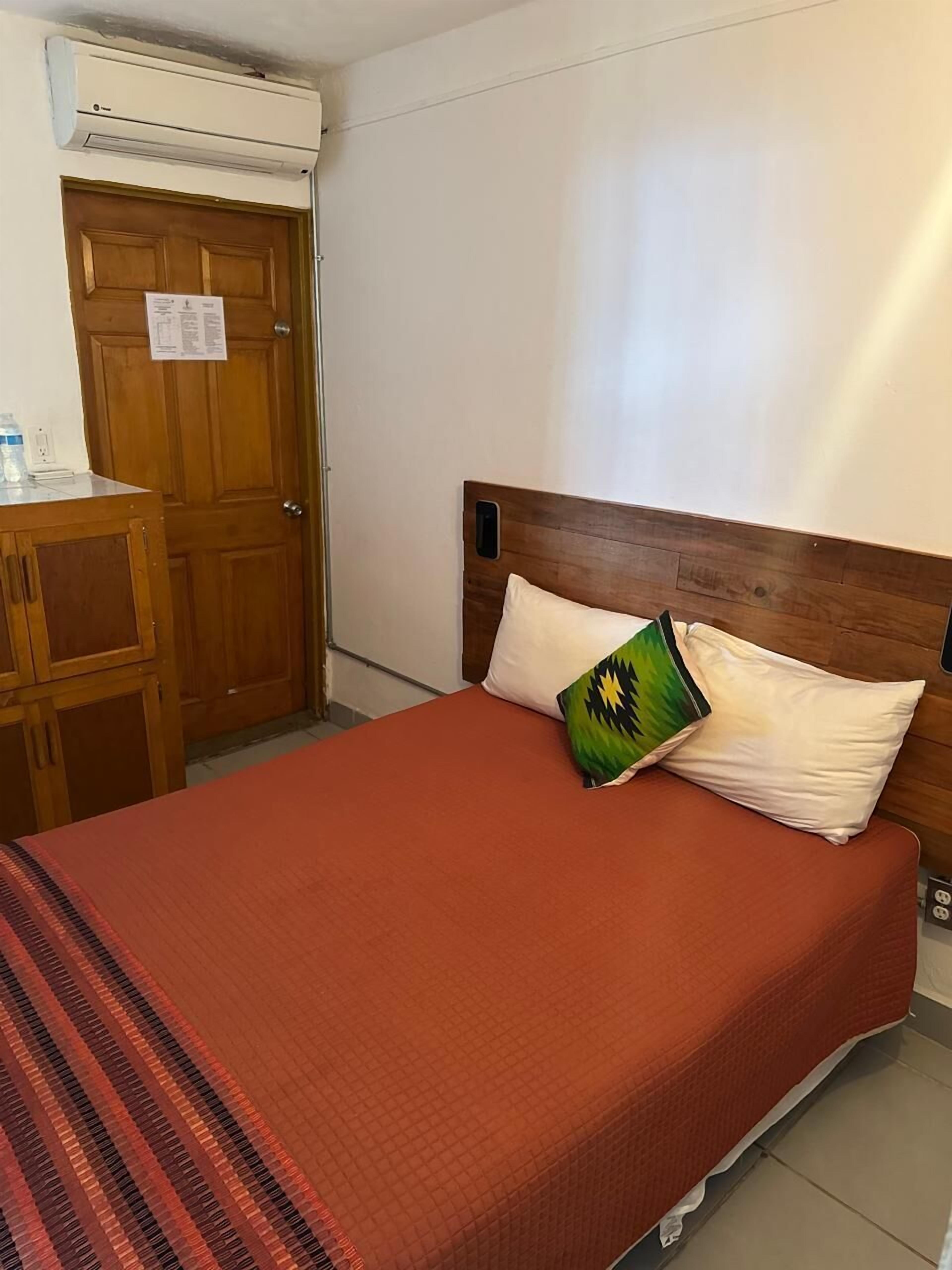 Una habitación con una cama, una puerta de madera y un equipo de aire acondicionado.