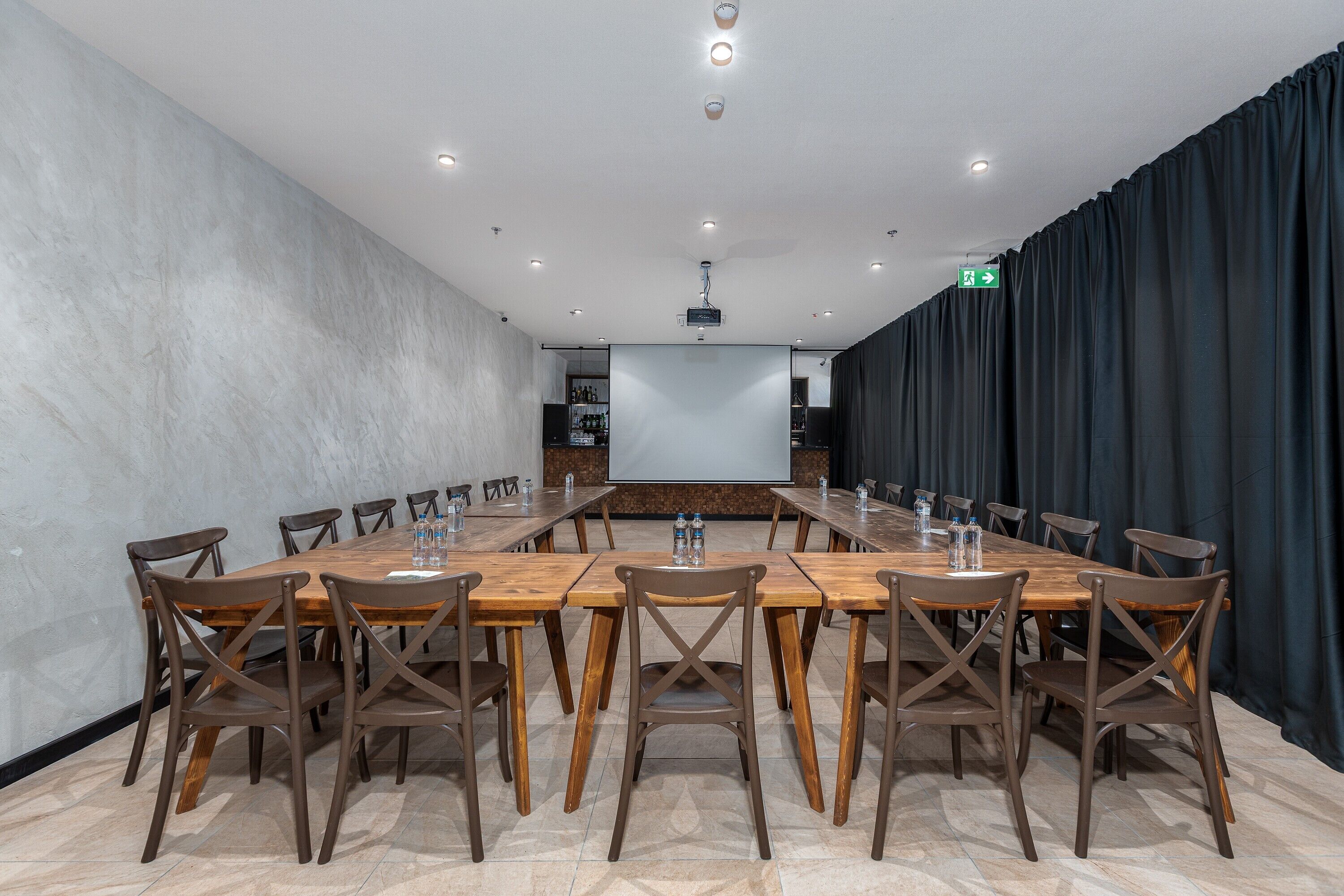 A conference room with a long table and chairs, a projector screen, and a water dispenser.