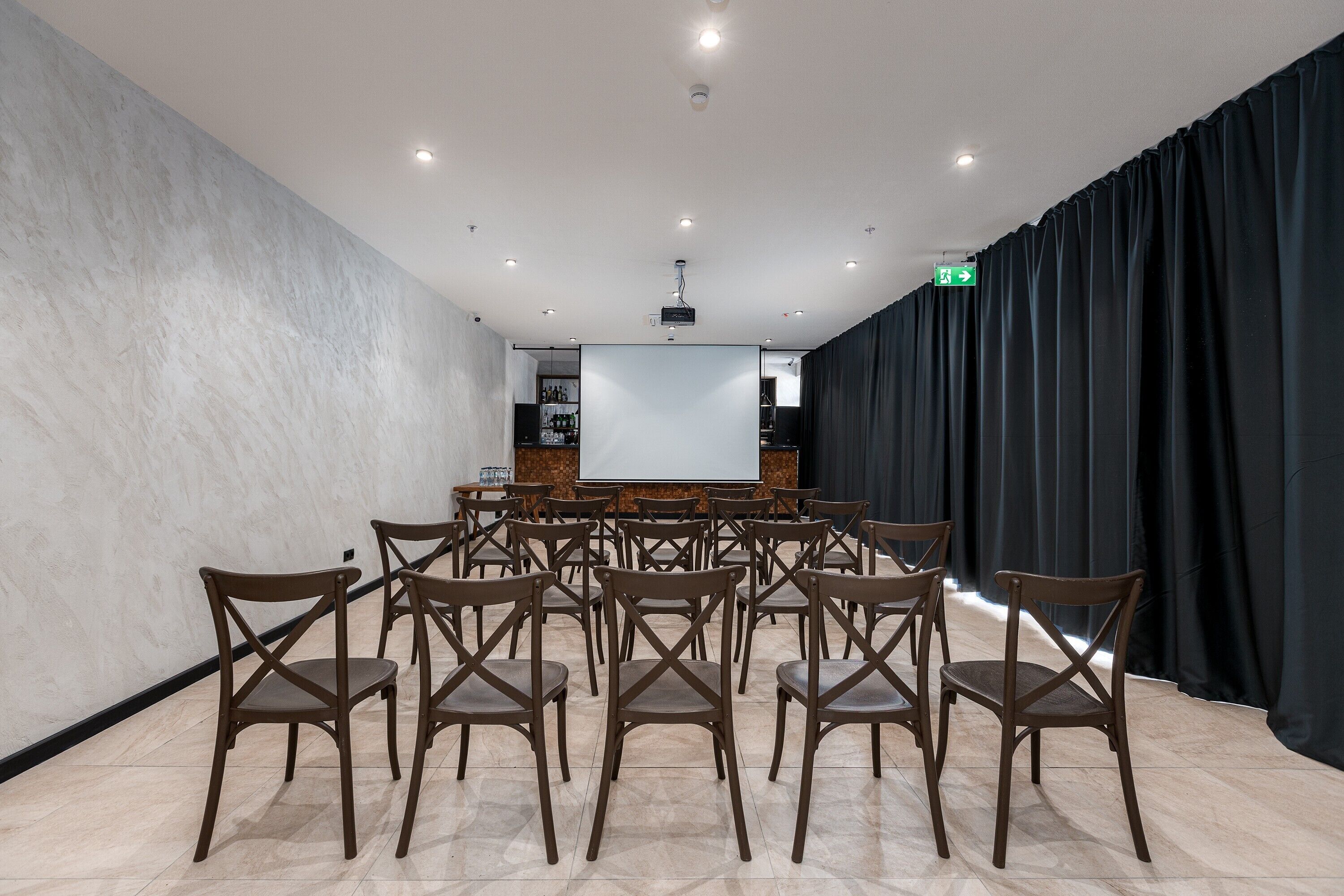 Ein Konferenzraum mit großem Bildschirm, mehreren Stühlen und einem Projektor.